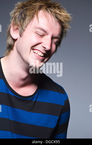 Junger Mann im gestreiften T-shirt lachen, studio Stockfoto