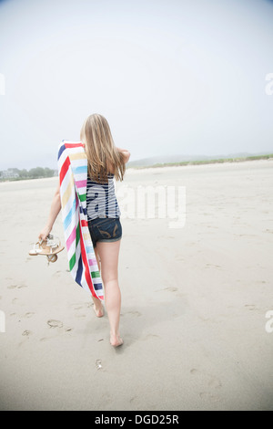 Junge Frau mit Handtuch am Strand zu Fuß Stockfoto