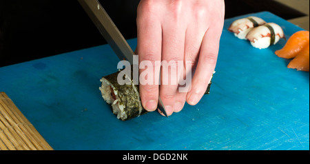 Sushi im Sushi-Bar. Sushi-Herstellung. Hände, die Sushi schneiden Stockfoto