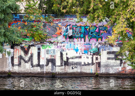 Graffiti-Künstler hinzufügen eines Tags auf die Graffiti bedeckt Wand an den Ufern der Spree, Berlin Stockfoto