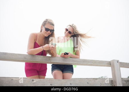 Junge Frauen, die Benutzung von Mobiltelefonen am pier Stockfoto