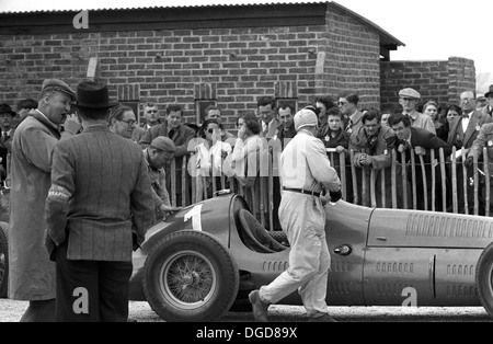 Mechaniker Luigi Parenti schiebt Dr Farina Maserati 4CLT im Montagebereich in Goodwood, England 1951. Stockfoto