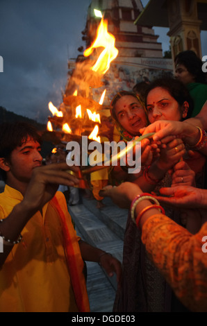 Anhänger, die die Wärme des heiligen Feuers von Aarti, Abend Ganga Aarti am Parmarth Niketan Ashram in Rishikesh, Indien Stockfoto