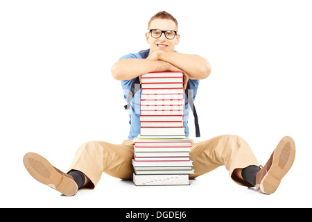 Lächelnd männlichen Studenten mit Schultasche auf einen Stapel Bücher Stockfoto