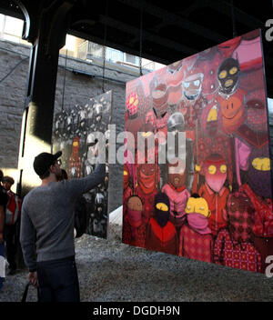New York, USA. 18. Oktober 2013. Graffiti-Künstler BANKSY, bekannt für seinen Stil Schablone arbeitet mit brasilianischen eineiige Zwillinge OS GEMEOS, bekannt für ihr gelb gefärbten Cartoon Volk für "Besser aus als In" street Art passiert überall in NYC. Die Stücke auf 24th St zwischen 10. & 11. St in West Chelsea gelegen. Die Gemälde sind hing an einer Railroad Trestle & bewacht um Verunstaltung zu verhindern. Bildnachweis: Nancy Kaszerman/ZUMAPRESS.com/Alamy Live-Nachrichten Stockfoto