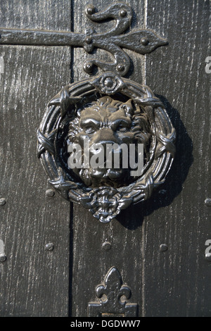 Löwenkopf klopft an einer schwarzen Holztür. Thaxted Village, Essex, Großbritannien Stockfoto