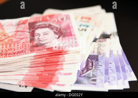 Bündel von Sterling £50, £20, £10 und £5 Noten vor schwarzem Hintergrund Stockfoto