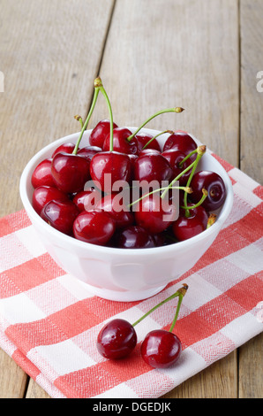 Keramikschale weiß Bio Kirschen auf Holztisch Stockfoto