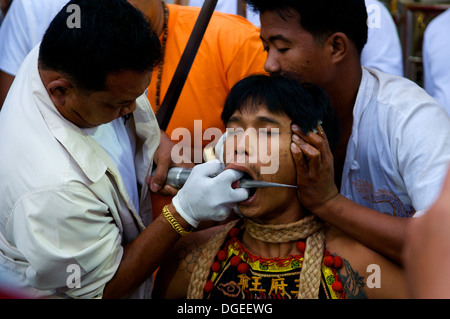 MA-Thong (Spirituosenmedium) wird während des Phuket Vegetarian Festival in Phuket Town, Thailand mit Piercing Gage durchbohrt. © Kraig Lieb Stockfoto