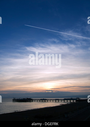 Sonnenuntergang und Flugzeug-Kondensstreifen über Brighton Pier, Sussex, UK Stockfoto