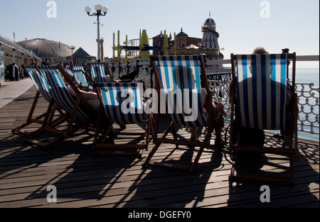 Menschen in Liegestühlen auf Brighton Pier, Sussex, UK Stockfoto