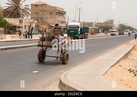 Senegal. Ein Pferdefuhrwerk teilt sich die Autobahn mit großen Lastwagen am Stadtrand von Dakar. Stockfoto