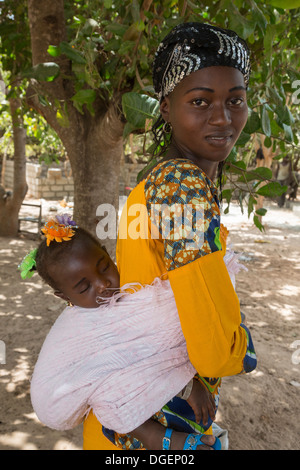 Junge Gambian Mutter tragen am Rücken, Fass Njaga Choi, North Bank Region, Gambia schlafenden Tochter. Stockfoto