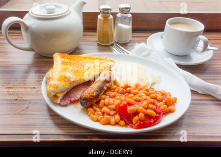 Café Essen ein kleines englisches Frühstück Speck gebraten Ei Wurst baked Beans und eine gebratene pflaumentomate und Tee serviert in Yorkshire Stockfoto