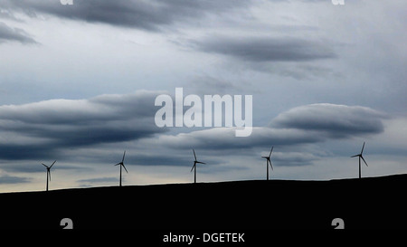 Fünf Windkraftanlagen auf einem Hügel, schwere Wolke hinter. Stockfoto