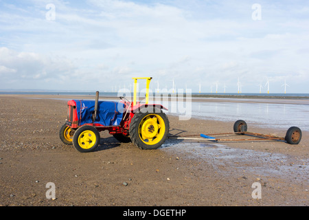 Fischers rote und gelbe Traktor für das Boot vom Strand Redcar Cleveland UK mit Windpark hinter starten Stockfoto