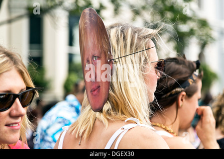 Junge Frau trägt eine Boris Johnson Gesichtsmaske hinter ihrem Kopf an der Notting Hill Carnival 2013, London, England Stockfoto