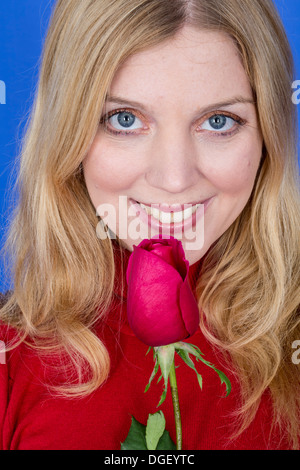 -Modell veröffentlicht. Attraktive junge Frau mit einer einzelnen roten Rose Stockfoto