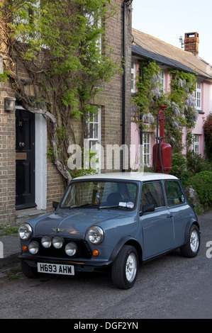 Oldtimer. Ein Austin Mini geparkt in der High Street von der malerischen Dorset Dorf Sydling St. Nikolaus. Dahinter befindet sich ein Vintage Zapfsäule. England. Stockfoto