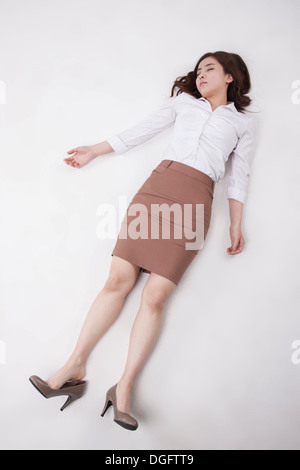 eine Geschäftsfrau, die auf dem Boden liegend Stockfoto