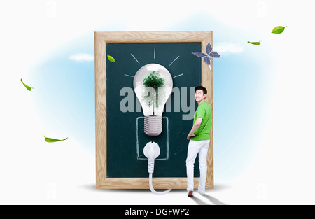 ein Mann steht neben einer Glühbirne mit einem Baum im Inneren Stockfoto