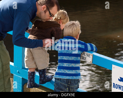 Zwei junge Burschen und Vater Blick über Zaun an der Fluss, Bude, Cornwall, UK Stockfoto