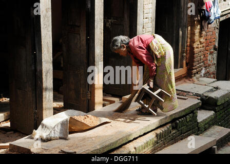 Frau in traditioneller Kleidung fegen die Boden, Bhaktapur, Kathmandu-Tal, Nepal, Asien Stockfoto