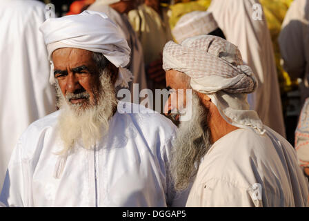 Omanische Männer in Tracht, Vieh oder Tiermarkt in Nizwa, Hajar al-Gharbi-Gebirge, Al Dakhliyah region Stockfoto