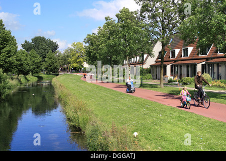 Radfahrer auf einem Radweg in einem Wohngebiet von Houten, eine niederländische Neustadt, in der Nähe von Utrecht, Niederlande. Stockfoto