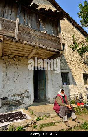 Albanische Frau sitzt vor einem alten Bauernhaus, Cerem, Valbona Nationalpark, albanische Alpen, Albanien, Balkan, Europa Stockfoto