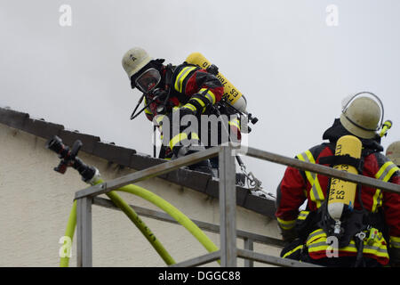 Feuerwehrleute Atemschutzgeräte beim Löschen eines Brandes Dach tragen, Fliesen entfernen das Dach, um Zugriff auf das Dach, Aichwald Stockfoto