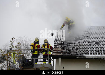 Feuerwehrleute Atemschutzgeräte beim Löschen eines Brandes Dach tragen, Fliesen entfernen das Dach, um Zugriff auf das Dach, Aichwald Stockfoto