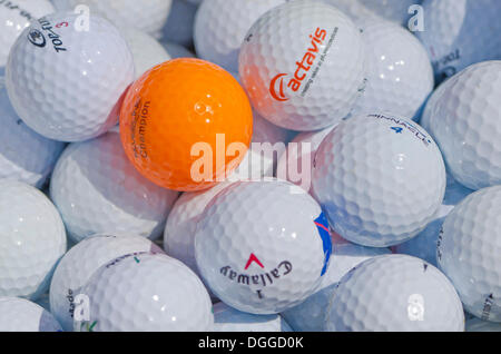 Viele weiße Golfbälle und einer orange Stockfoto