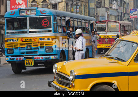 Straßenszene mit öffentlichen Bus, Taxi und Polizist, Kalkutta, Indien, Asien Stockfoto