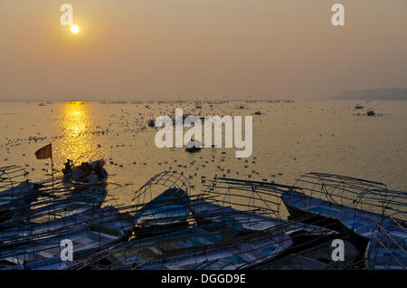 Sonnenaufgang über Schiffe mit Pilgern am Sangam, dem Zusammenfluss der heiligen Flüsse Ganges und Yamuna Saraswati in Allahabad, Indien Stockfoto