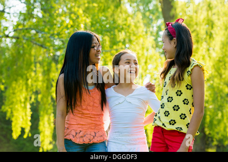 Drei Mädchen im Park mit Arme umeinander Stockfoto