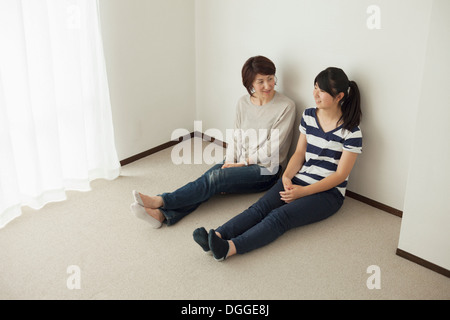 Mutter und Tochter im Teenageralter sitzen auf Boden, Porträt Stockfoto