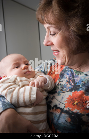 Ältere Frau hält Baby Boy, lächelnd Stockfoto