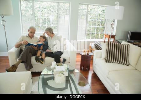Großeltern zeigen junge Fotoalbum auf sofa Stockfoto