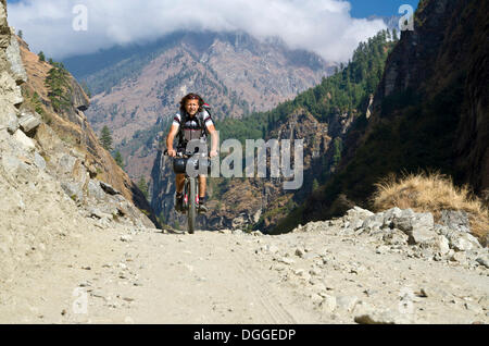 Touristische, Radfahren auf einem Schotterweg in Marsyangdi Yuni-Tal, Annapurna Region Nepal Stockfoto