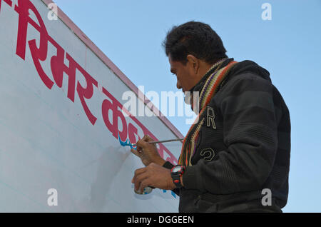 Mann, die Malerei roter Hindi Buchstaben auf eine weiße Tafel, Pokhara, Nepal Stockfoto
