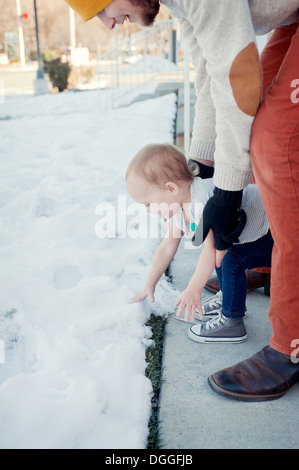 Junges Mädchen mit Vater beobachtete Schnee berühren Stockfoto