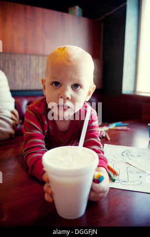 Kleiner Junge für Milchshake im Café zu erreichen Stockfoto