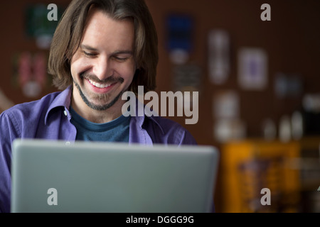 Porträt des jungen Mannes mit am Computer im café Stockfoto