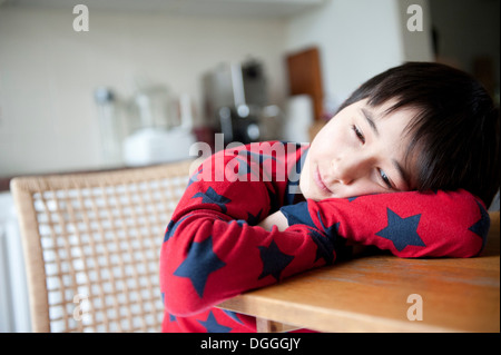 Junge im Pyjama auf Ellbogen auf den Tisch Stockfoto