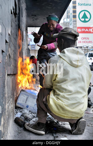 Straßenkinder, wärmten sich um ein Feuer in den frühen Morgenstunden, Stadtteil Hillbrow, Johannesburg, Südafrika, Afrika Stockfoto