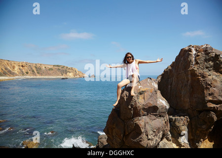 Junge Frau sitzt auf den Felsen, Palos Verdes, Kalifornien, USA Stockfoto