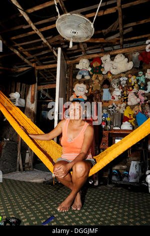 Frau sitzt auf einer Hängematte in einer einfachen Holzhütte in einem Armenviertel von Cancun, Halbinsel Yucatan, Quintana Roo, Mexiko Stockfoto