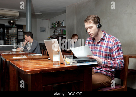 Junger Mann mit Kopfhörern mit Laptop im café Stockfoto