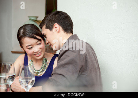 Junges Paar im Restaurant Mann flüstert Stockfoto